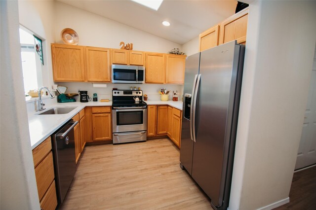 kitchen featuring light hardwood / wood-style floors, sink, vaulted ceiling, light brown cabinets, and appliances with stainless steel finishes