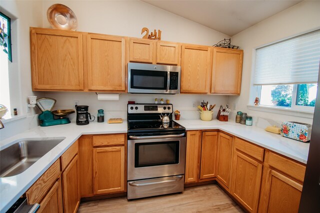 kitchen with stainless steel appliances, lofted ceiling, and light wood-type flooring