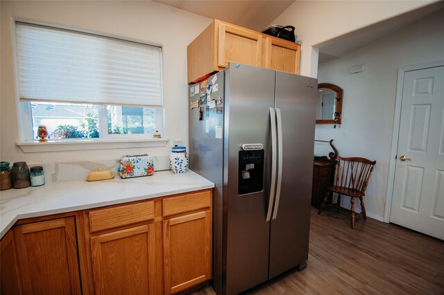 kitchen featuring stainless steel fridge, lofted ceiling, light stone countertops, and dark wood-type flooring