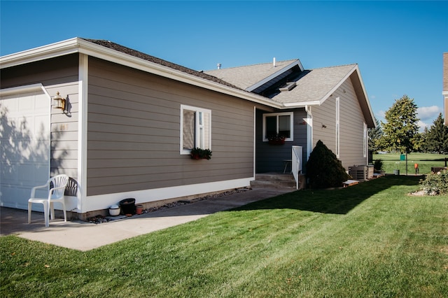 view of side of home featuring a yard, a garage, and central AC unit