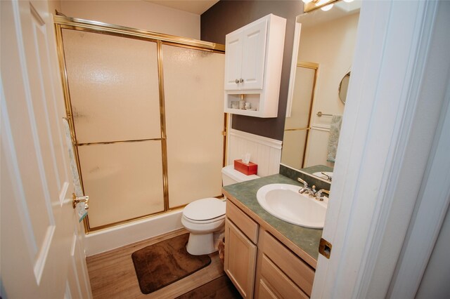 bathroom with wood-type flooring, walk in shower, vanity, and toilet