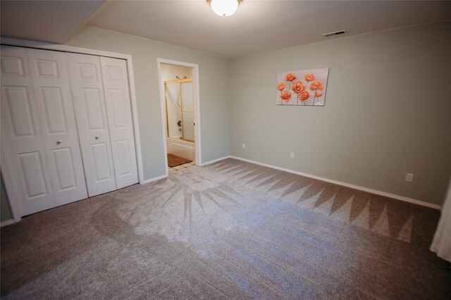 unfurnished bedroom with ensuite bath, a closet, and carpet flooring