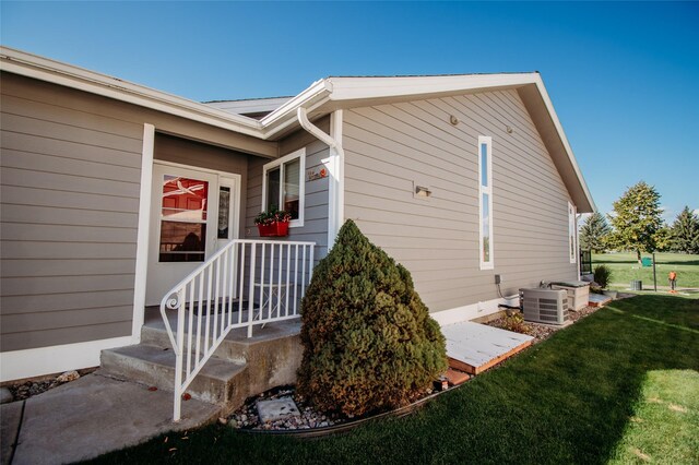 view of property exterior with a lawn and central AC