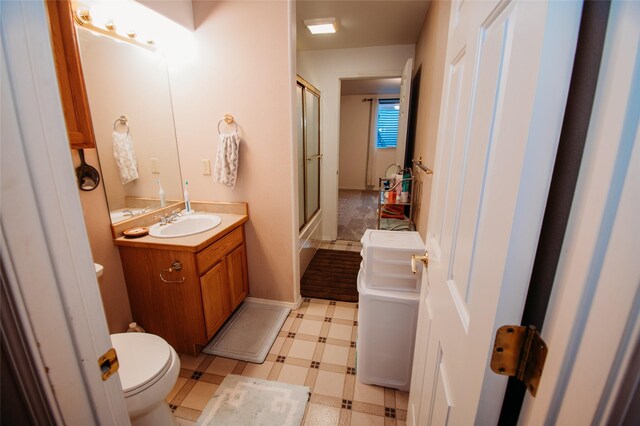 bathroom with vanity, toilet, and a shower with door