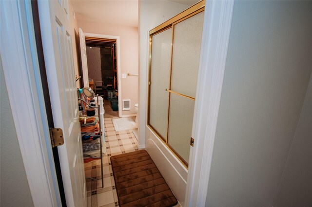 bathroom featuring bath / shower combo with glass door and toilet