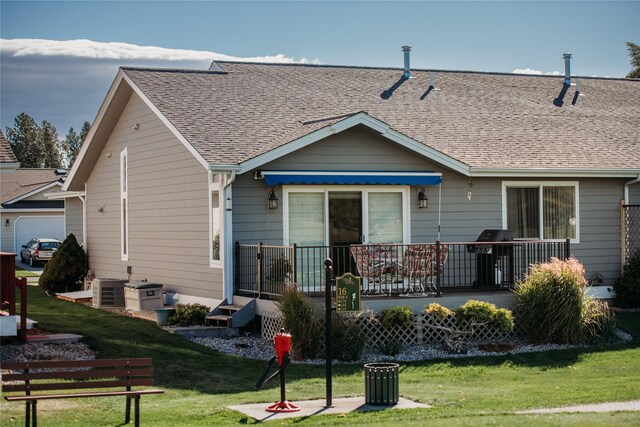 back of house with central AC unit and a yard