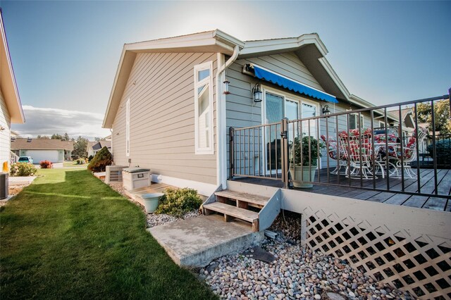 view of side of home with a deck, a yard, and central AC