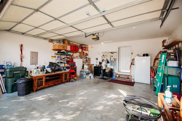 garage featuring a garage door opener, electric panel, and white fridge