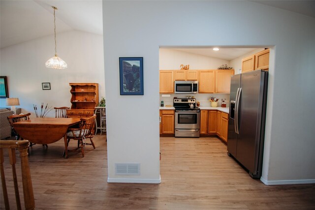 kitchen with light hardwood / wood-style flooring, lofted ceiling, appliances with stainless steel finishes, and decorative light fixtures