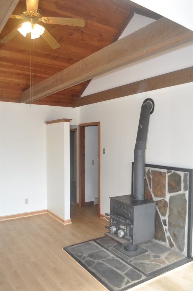 unfurnished living room with wood ceiling, lofted ceiling with beams, ceiling fan, and a wood stove