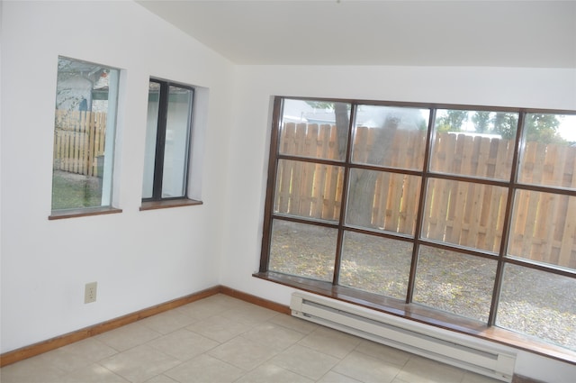 tiled spare room featuring lofted ceiling, baseboard heating, and plenty of natural light