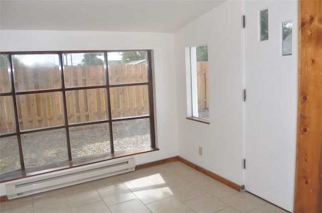 tiled empty room featuring a baseboard radiator and vaulted ceiling