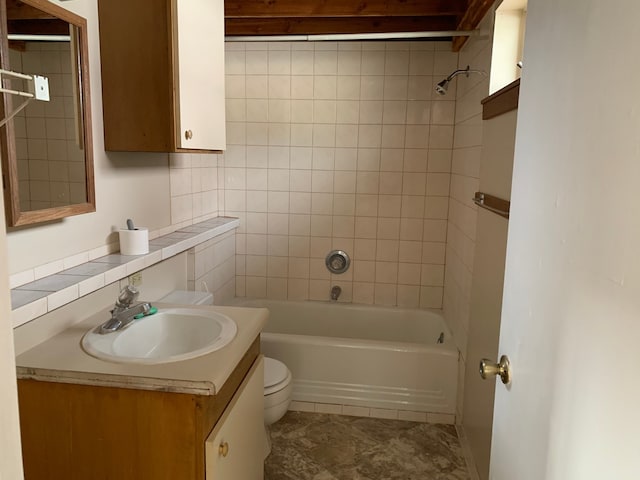 full bathroom with decorative backsplash, tiled shower / bath, vanity, and toilet