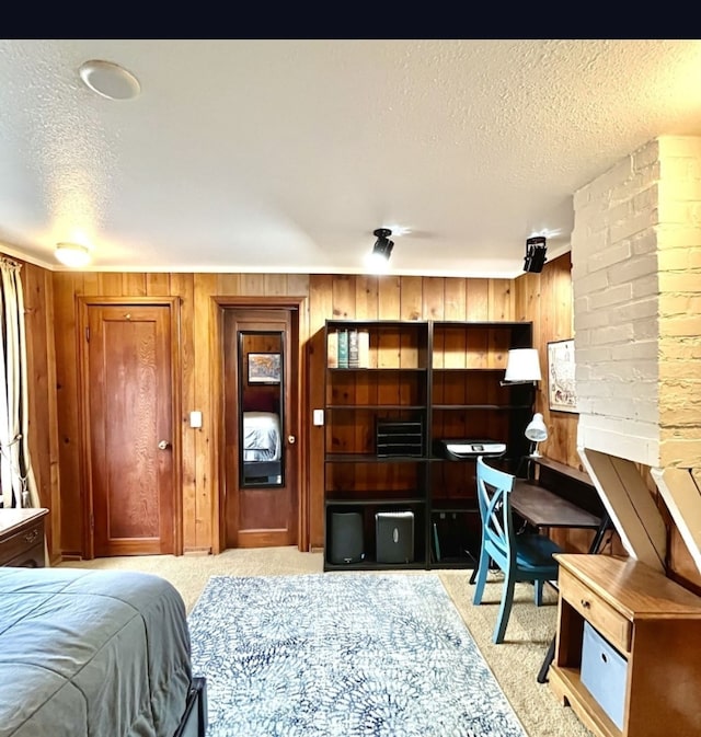 bedroom with light carpet, a textured ceiling, and wooden walls