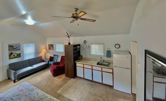 carpeted living room with lofted ceiling, ceiling fan, and sink