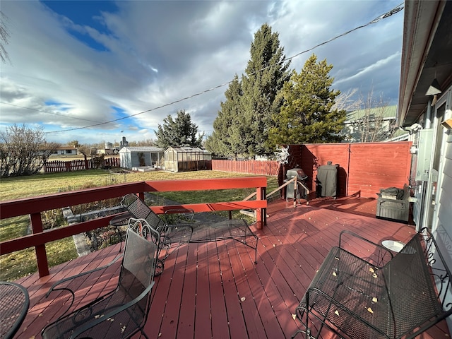 wooden deck featuring a lawn, area for grilling, and a shed