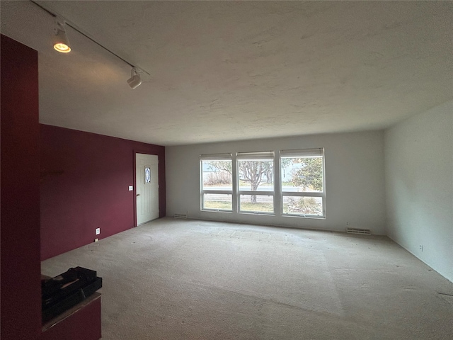 unfurnished living room with carpet flooring, rail lighting, and a textured ceiling