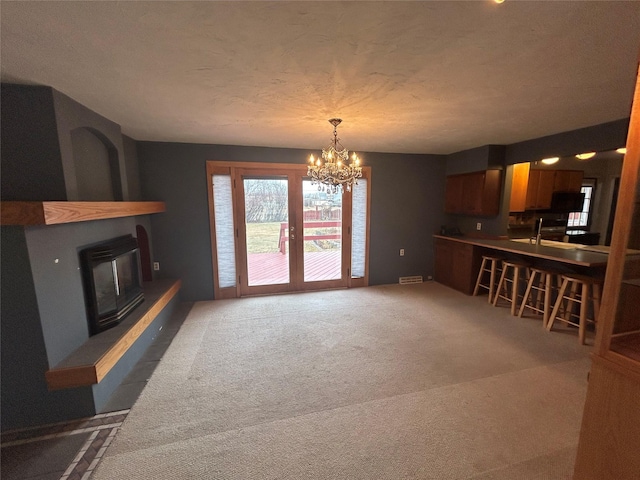 214 Laura St, Augusta, MT 59410 - unfurnished living room with carpet, a chandelier, a large fireplace, and a textured ceiling