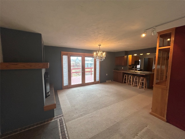 unfurnished living room featuring carpet floors, a chandelier, a textured ceiling, and rail lighting