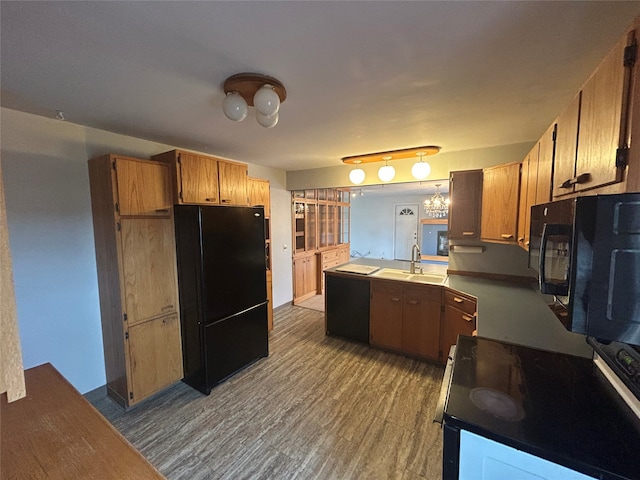 kitchen featuring sink, an inviting chandelier, kitchen peninsula, hardwood / wood-style floors, and black appliances