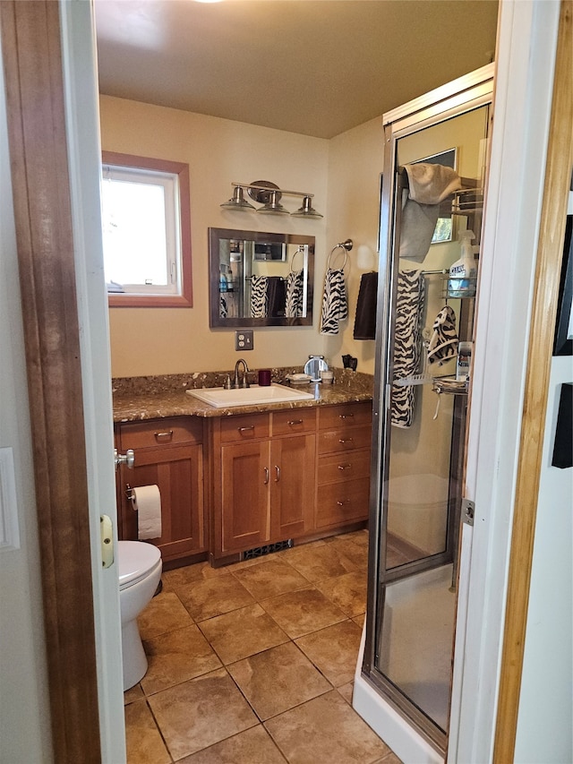 bathroom with tile patterned floors, vanity, toilet, and a shower with door