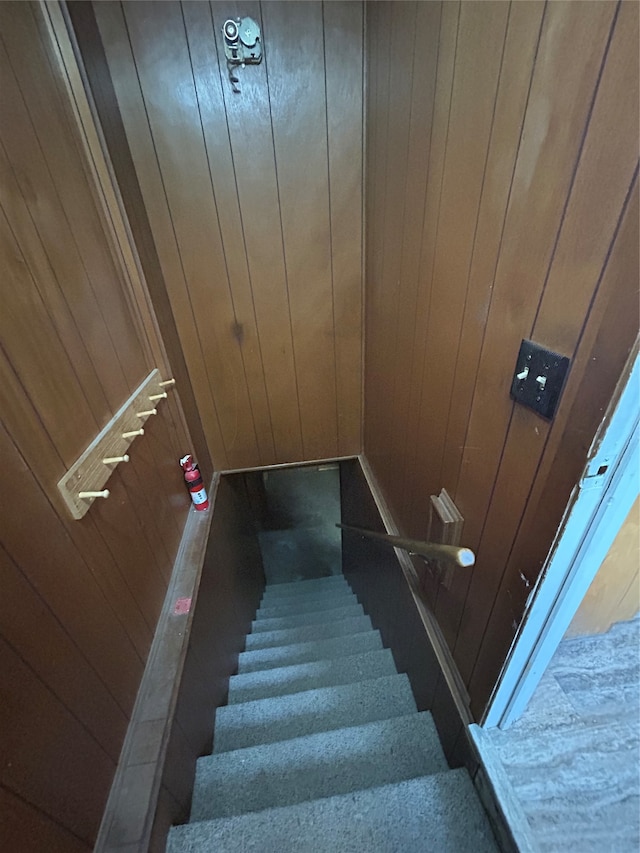 stairway featuring wood walls