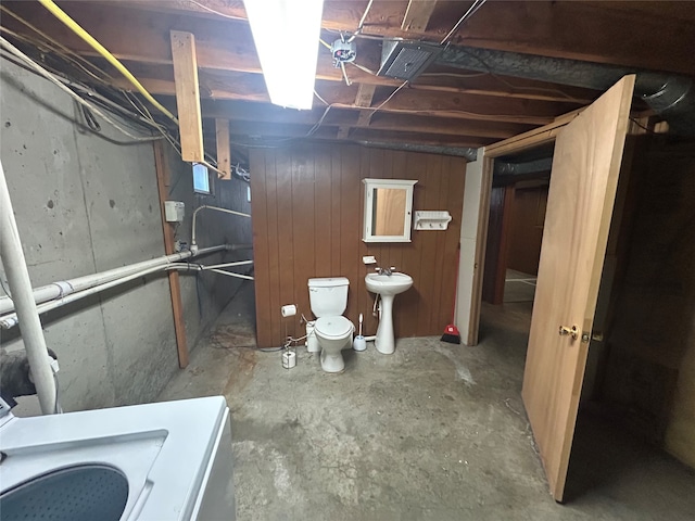 basement with wood walls, sink, and washer / clothes dryer