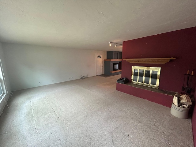 214 Laura St, Augusta, MT 59410 - unfurnished living room with a glass covered fireplace, carpet flooring, and track lighting