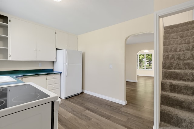 kitchen featuring stove, white cabinets, light hardwood / wood-style floors, and white fridge