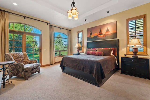 bedroom featuring a raised ceiling, a chandelier, and light colored carpet