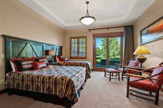 carpeted bedroom featuring access to outside and a tray ceiling