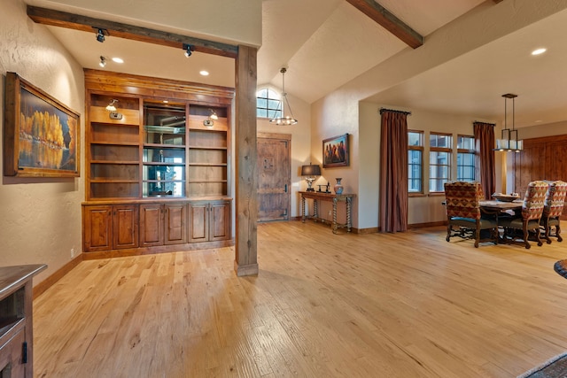 interior space featuring light wood-type flooring, vaulted ceiling with beams, and a chandelier