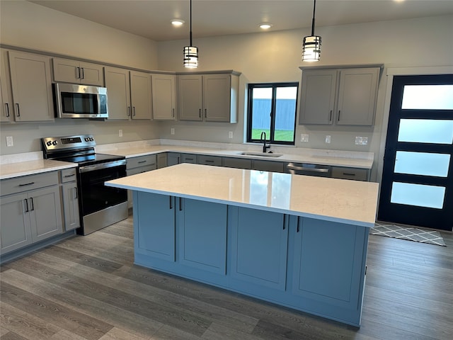 kitchen with hanging light fixtures, a kitchen island, gray cabinets, hardwood / wood-style floors, and sink