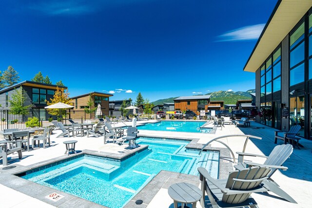 view of swimming pool with a patio, a hot tub, and a mountain view