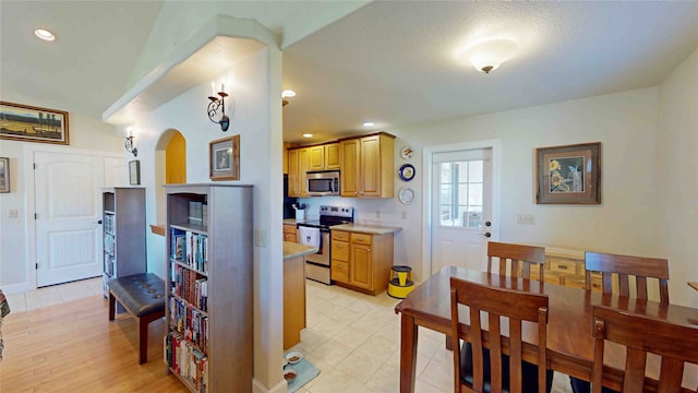 kitchen with appliances with stainless steel finishes, a textured ceiling, and light wood-type flooring