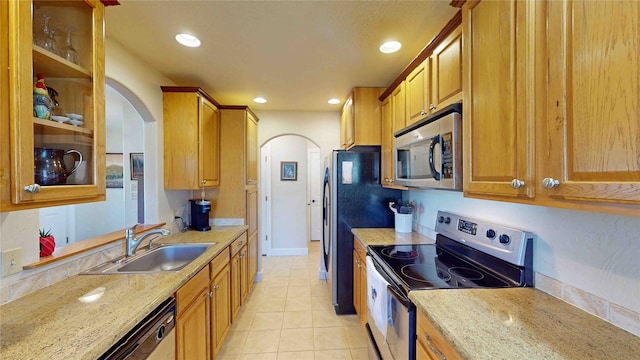 kitchen featuring light stone countertops, stainless steel appliances, light tile patterned flooring, and sink