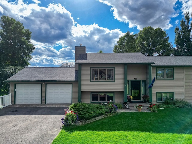 raised ranch featuring a front yard and a garage