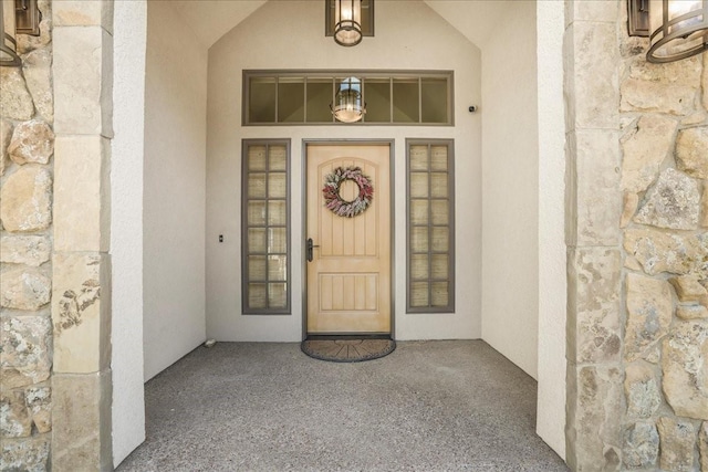 doorway to property with stucco siding and stone siding