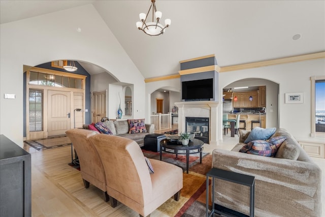 living room featuring high vaulted ceiling, an inviting chandelier, and light hardwood / wood-style flooring