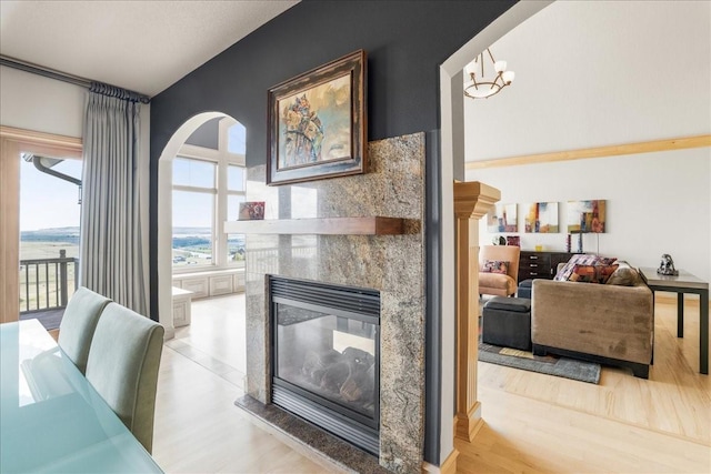 interior space featuring light wood finished floors, arched walkways, an inviting chandelier, and a fireplace
