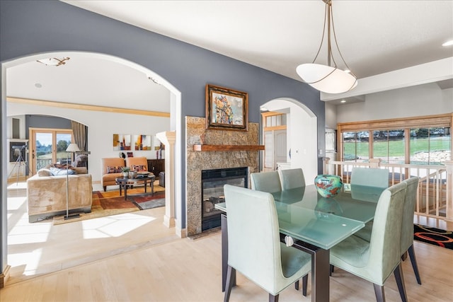 dining room with a healthy amount of sunlight, light hardwood / wood-style flooring, and a stone fireplace