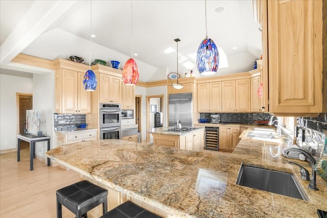 kitchen with light stone counters, built in appliances, beverage cooler, and a sink