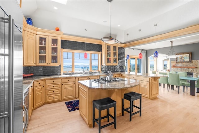 kitchen with decorative light fixtures, kitchen peninsula, a breakfast bar area, a kitchen island, and appliances with stainless steel finishes