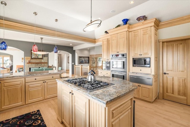 kitchen with light brown cabinetry, stainless steel appliances, a warming drawer, and arched walkways