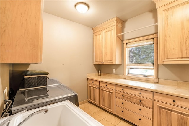 washroom with sink, washing machine and clothes dryer, light tile patterned floors, and cabinets