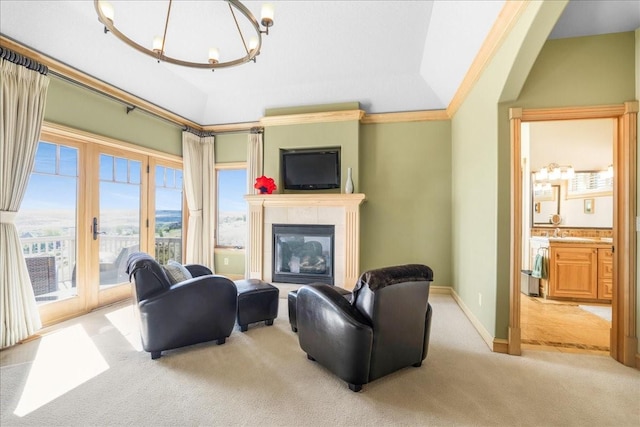 carpeted living area featuring a notable chandelier, baseboards, lofted ceiling, and a glass covered fireplace