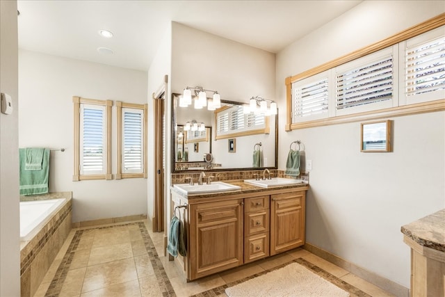 bathroom with a relaxing tiled tub, tile patterned flooring, a wealth of natural light, and vanity