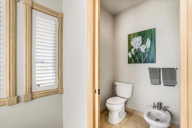 bathroom featuring toilet, tile patterned floors, a bidet, and baseboards