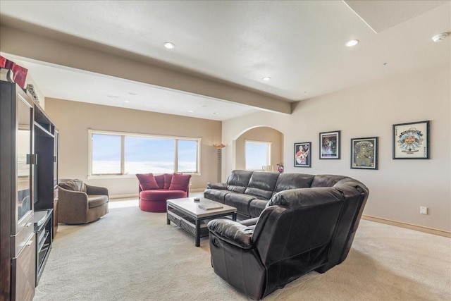 living area with recessed lighting, arched walkways, light colored carpet, and baseboards