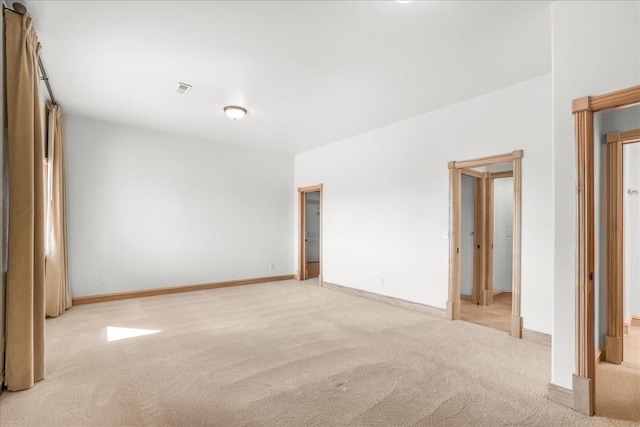 spare room featuring baseboards, visible vents, and light carpet